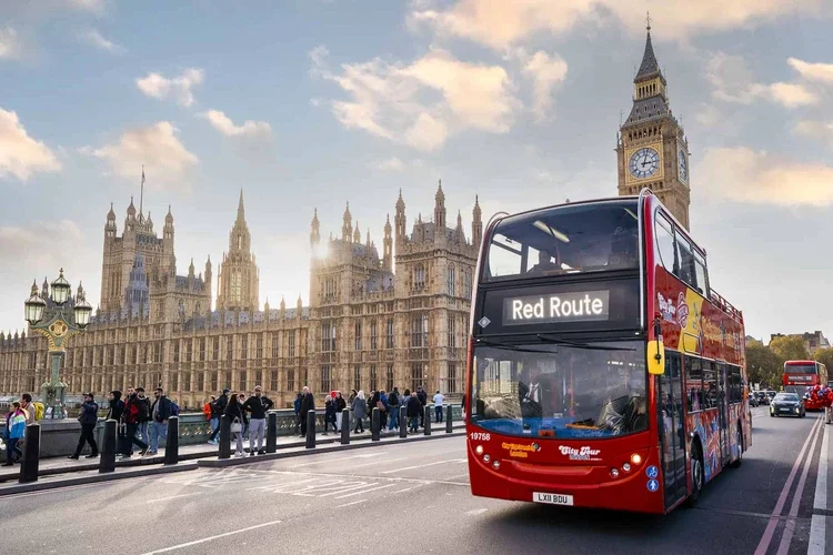 City Sightseeing London Red Route open-top bus crossing Westminster Bridge past the Houses of Parliament and Big Ben